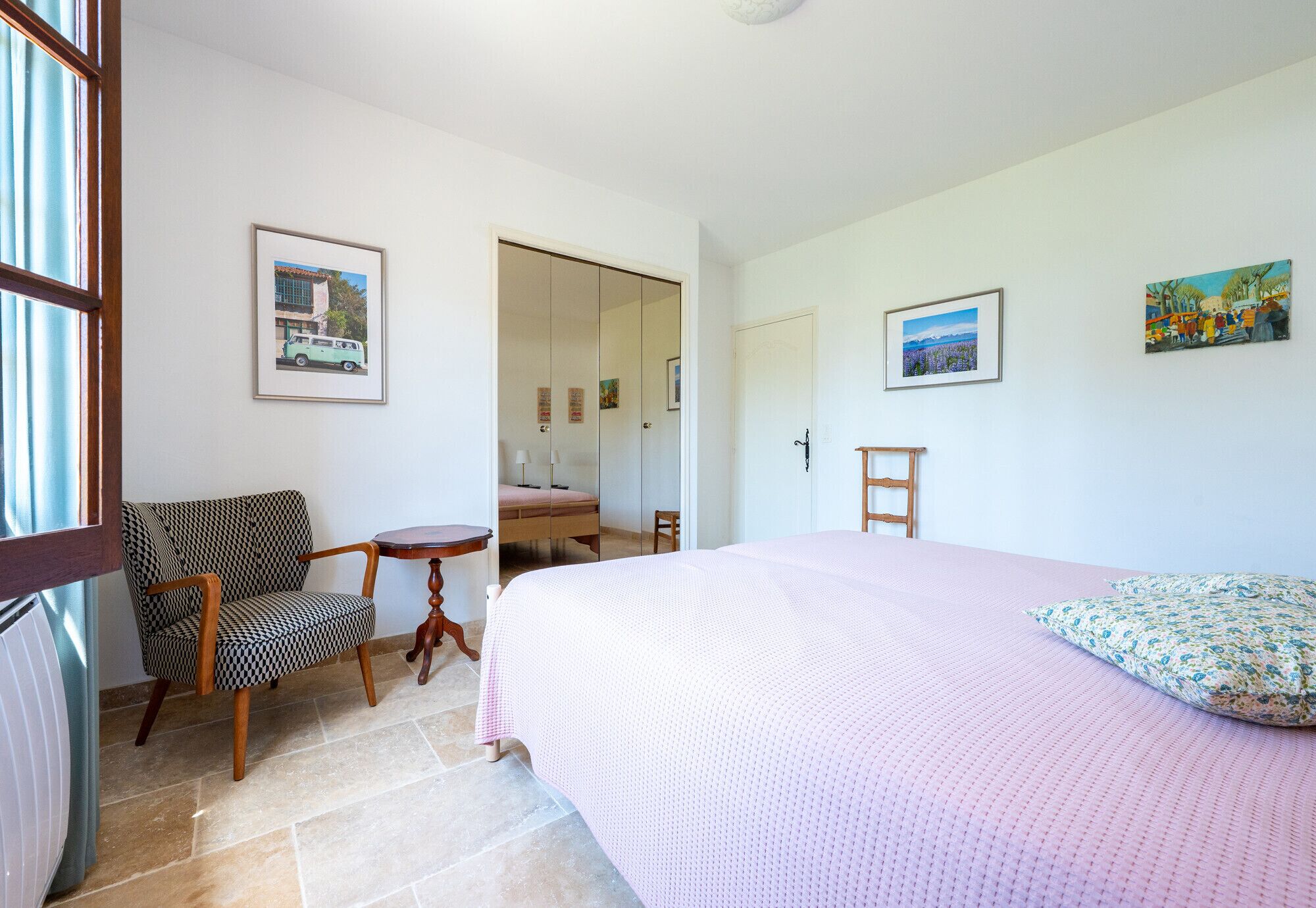 A bedroom with a bed, a chair, a table, and a mirror.