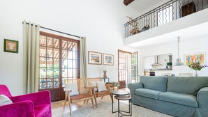 Uma sala de estar ampla com sofá, cadeiras, uma mesa de jantar e uma varanda com guarda-corpo.