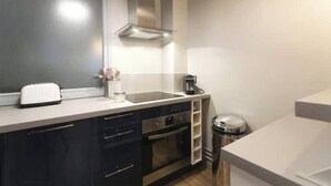 A modern kitchen with a stainless steel range hood, a toaster, a coffee maker, and a trash can. - Spacious, recently renovated apartment near the Louvre (Île-de-France)