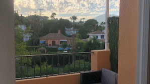 Un balcón con vistas a una zona residencial, un sofá y una pequeña mesa.