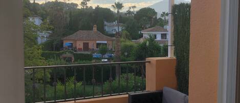 A balcony with a view of a residential area, a sofa, and a small table.
