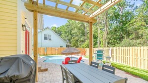 Eine überdachte Terrasse mit Pool, Gartenmöbeln und einem Holzzaun.