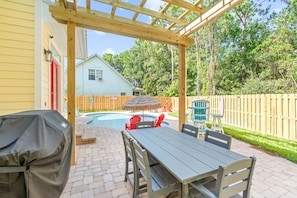 A covered patio with a pool, outdoor furniture, and a wooden fence. - The Love Bug: Private Pool, Golf Cart & Fire Pit, Sleeps 16 & Pet Friendly (Panama City Beach)