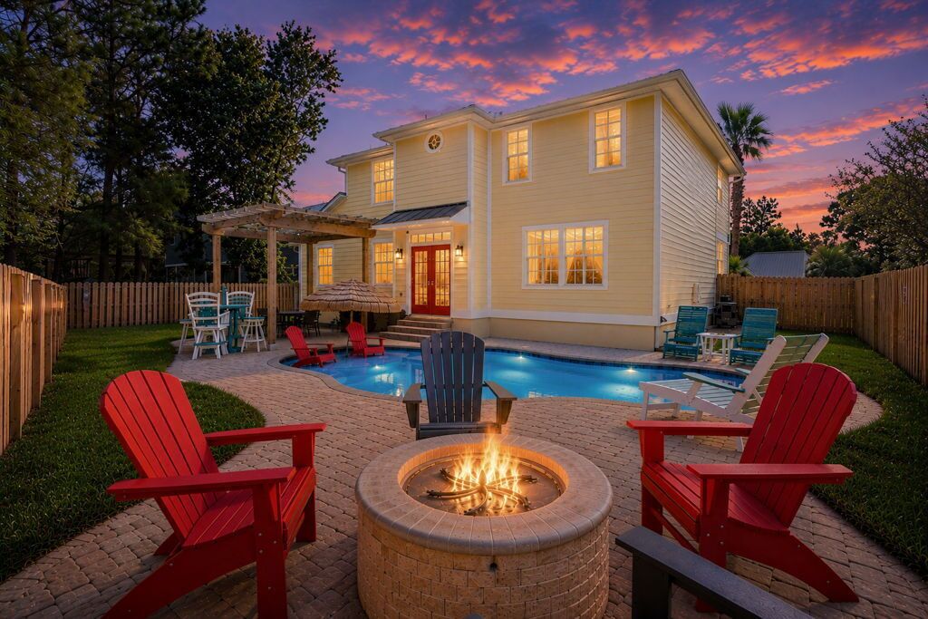 A two-story house with a swimming pool, outdoor seating, and a fire pit.