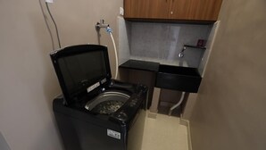 Una safareig reduït amb rentadora, un rentapous i una petita superfície de treball.