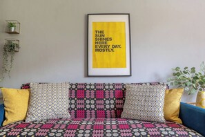 A room with a framed inspirational quote on the wall, a patterned sofa, and two potted plants. - #06 Riverside Retreat| Near the NEC| Guest for 6 (Coleshill)