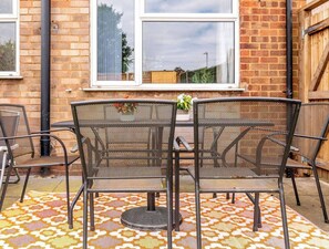 A patio area with a table and chairs, a patterned rug, and a brick wall with windows. - #06 Riverside Retreat| Near the NEC| Guest for 6 (Coleshill)
