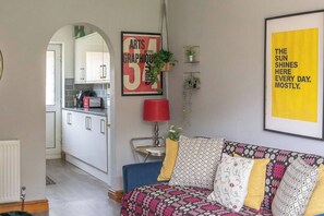 A living room with a sofa, a red lamp, and a framed poster on the wall. - #06 Riverside Retreat| Near the NEC| Guest for 6 (Coleshill)