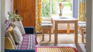 A cozy room with a wooden door, a blue sofa, a dining table with chairs, and a hanging light fixture. - #06 Riverside Retreat| Near the NEC| Guest for 6 (Coleshill)