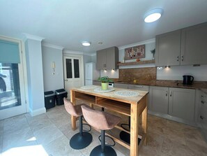 A modern kitchen with a wooden island, bar stools, and a built-in oven. - Elegant 4BDR 4BA Luxury Home Heart of Rathmines (Dublin)