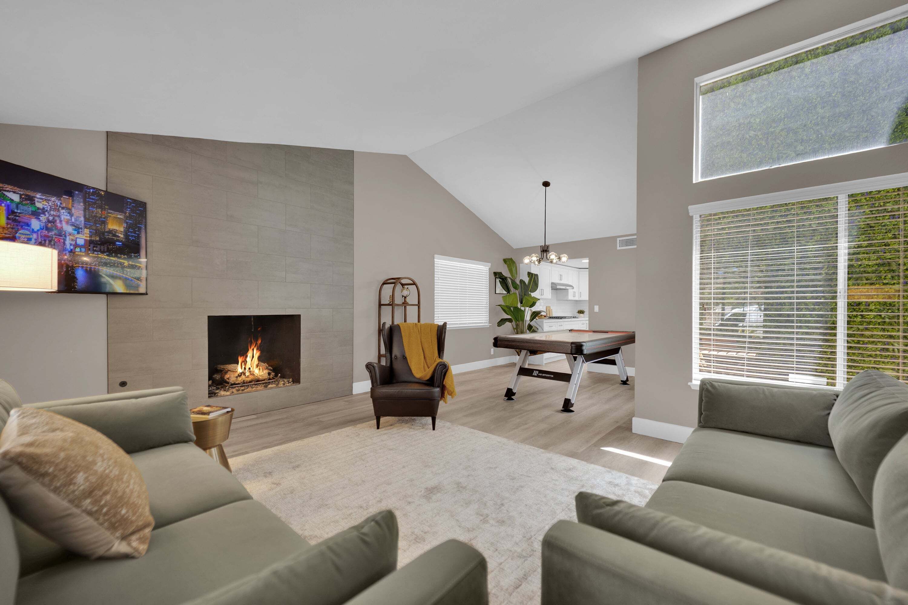 A modern living room with a fireplace, a dining area, and a kitchen in the background.