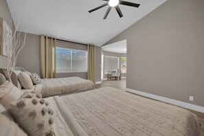 Un dormitorio con cama, ventilador de techo y vista a otra habitación.