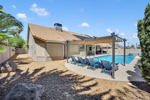 Ein Wohnhaus mit Schwimmbad, überdachter Terrasse und eingezäunter Garten.
