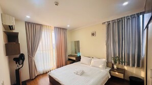 A hotel room with a bed, bedside table, lamp, and a window with curtains. - Green Valley EmHouse (Ho Chi Minh City)