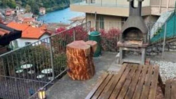 A balcony with a grill, a wooden bench, and a view of a lake and mountains. - NEW LarioView Suites – Apartment with Private Jacuzzi and Terrace with Lake Views (Argegno)