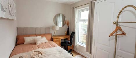Une chambre à coucher comprenant un lit, un bureau, une chaise, un miroir et une armoire.