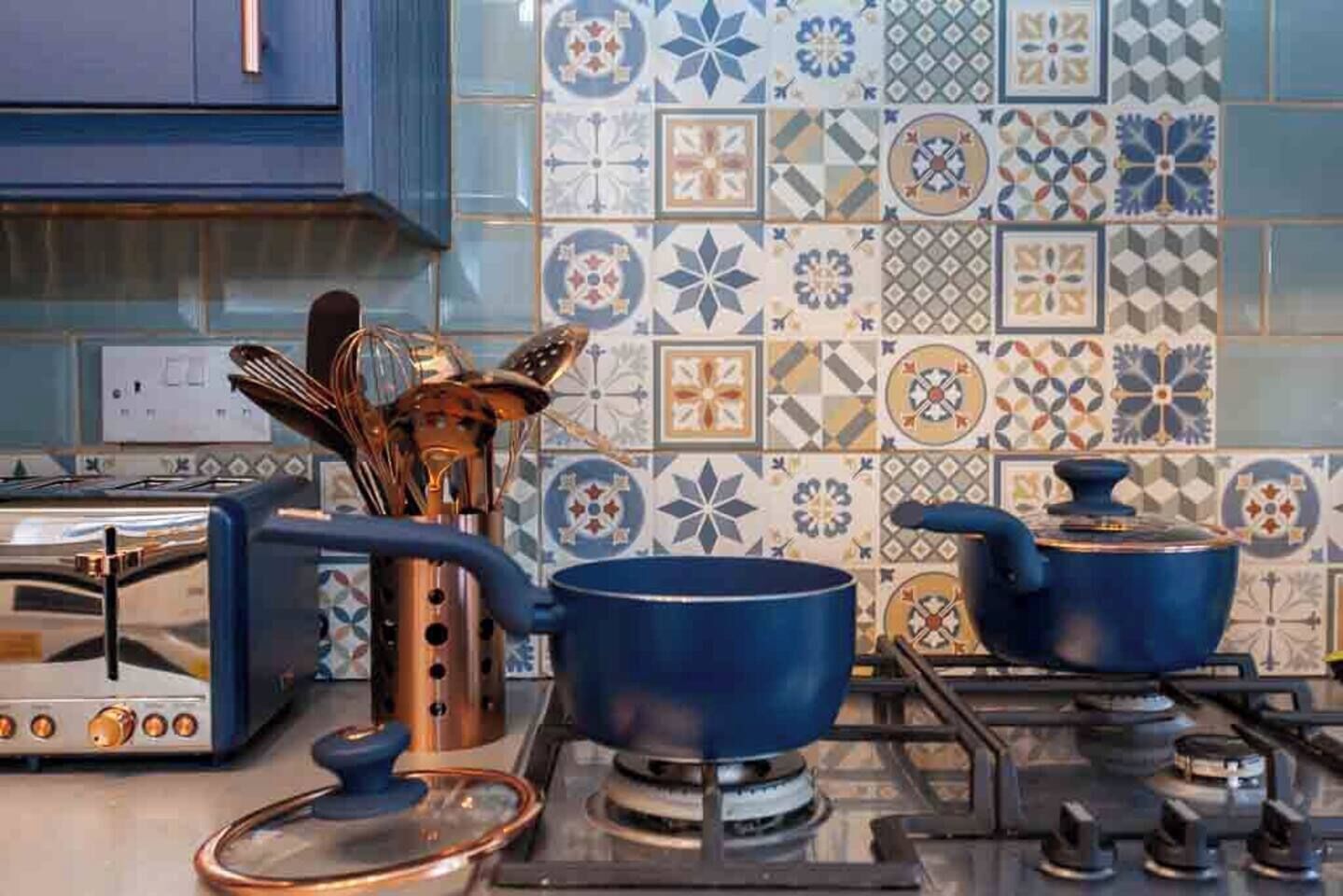 A kitchen with a gas stove, pots, a toaster, and a utensil holder.