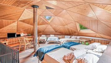 An interior with a high, sloped ceiling, multiple beds, a seating area, and a central column.