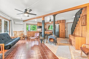 A spacious living area with a fireplace, wooden furniture, and a kitchen in the background. - Whispering Oaks Dome Retreat / Sleeps 9 / Private Woodland Escape (Saint Croix Falls)