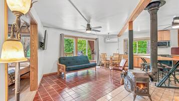 A spacious living area with a sofa, dining table, chairs, a fireplace, and a view of the outdoors.
