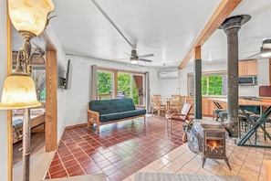 A spacious living area with a sofa, dining table, chairs, a fireplace, and a view of the outdoors.