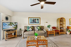 A living room with a television, sofa, coffee table, and a ceiling fan. - Hawaiian Getaway | 1BR Walk to Beach (Kihei)