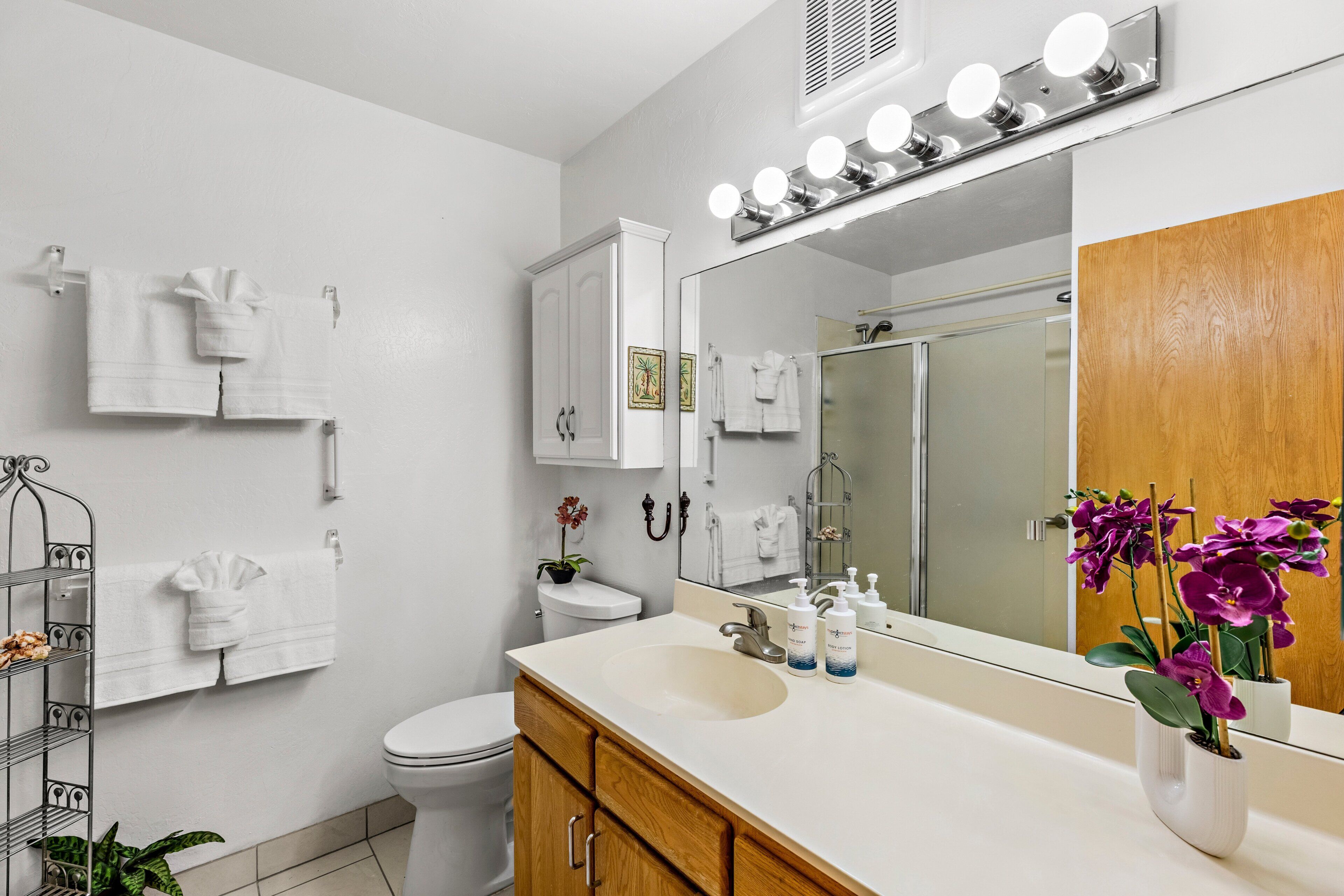 A bathroom with a vanity, sink, mirror, and towel rack.