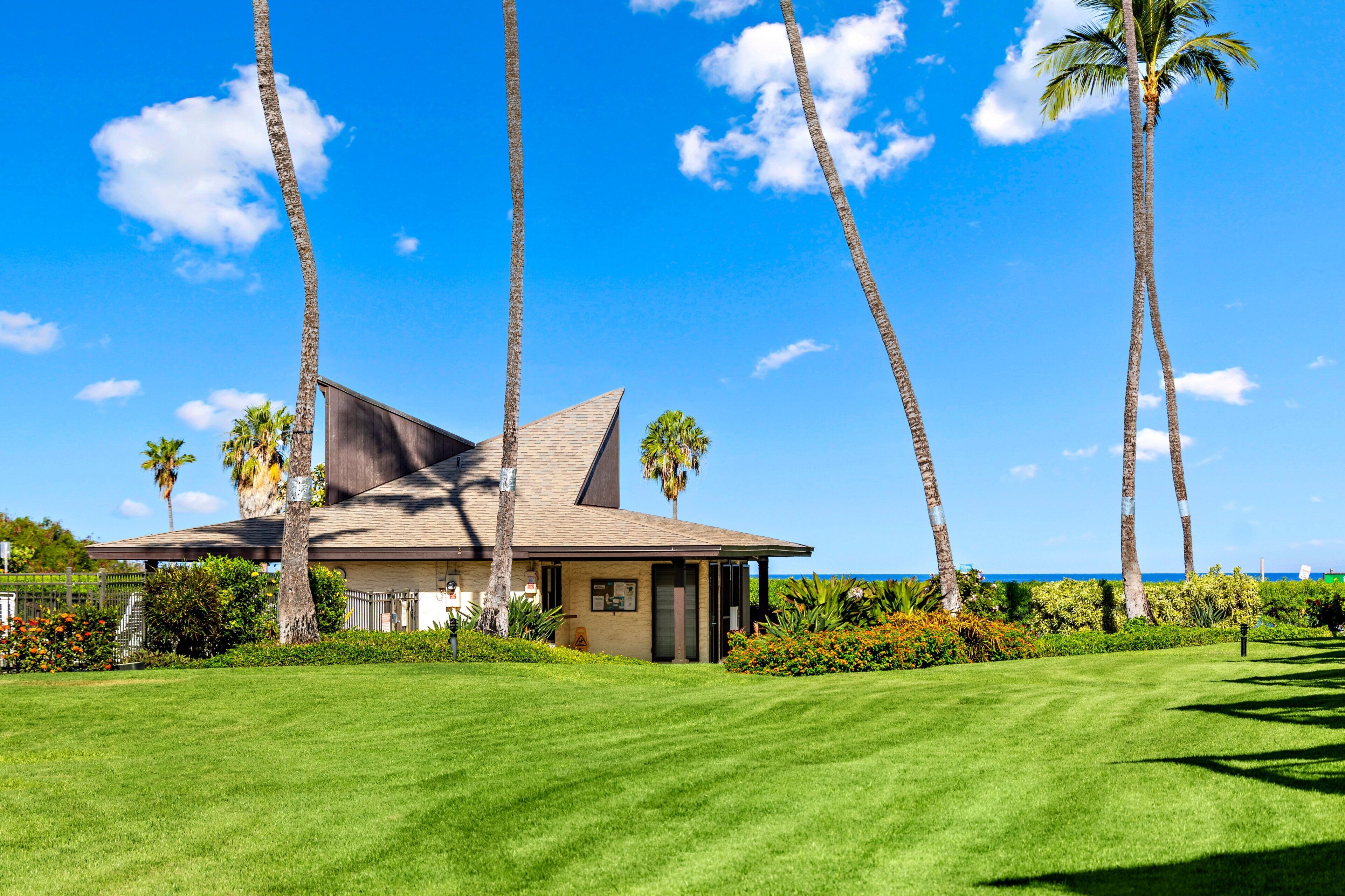 A house with a sloped roof, surrounded by a well-maintained lawn and palm trees.