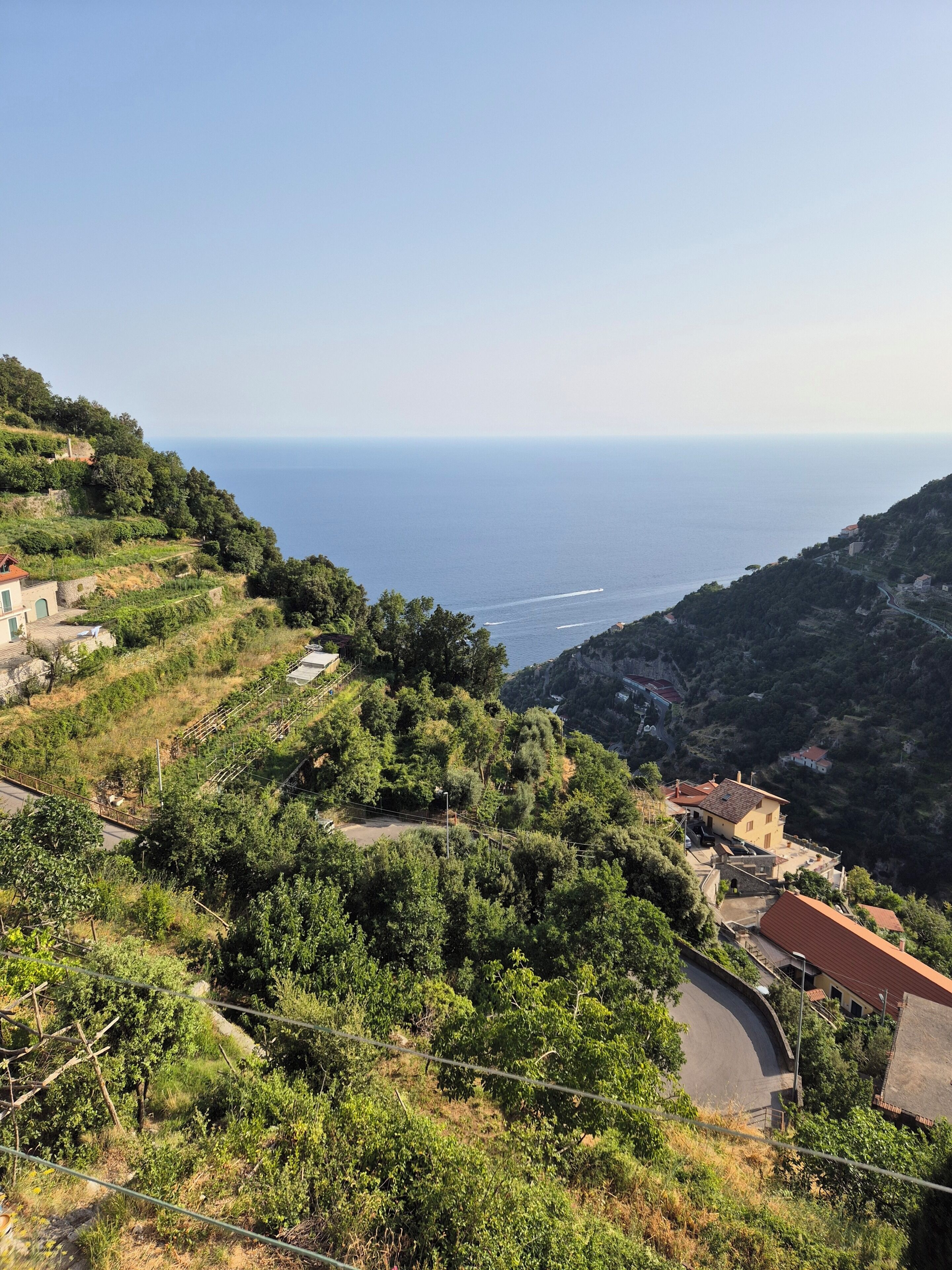 A coastal landscape with a winding road, buildings, and greenery.