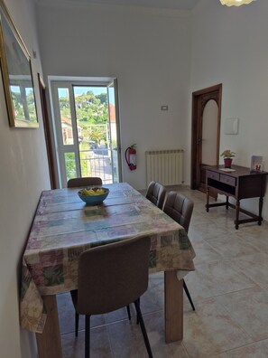 A dining area with a table, chairs, a fire extinguisher, and a view through a door. - A starting point for the Path of the Gods, Amalfi, Pompeii, Positano, Capri (San Lazzaro)