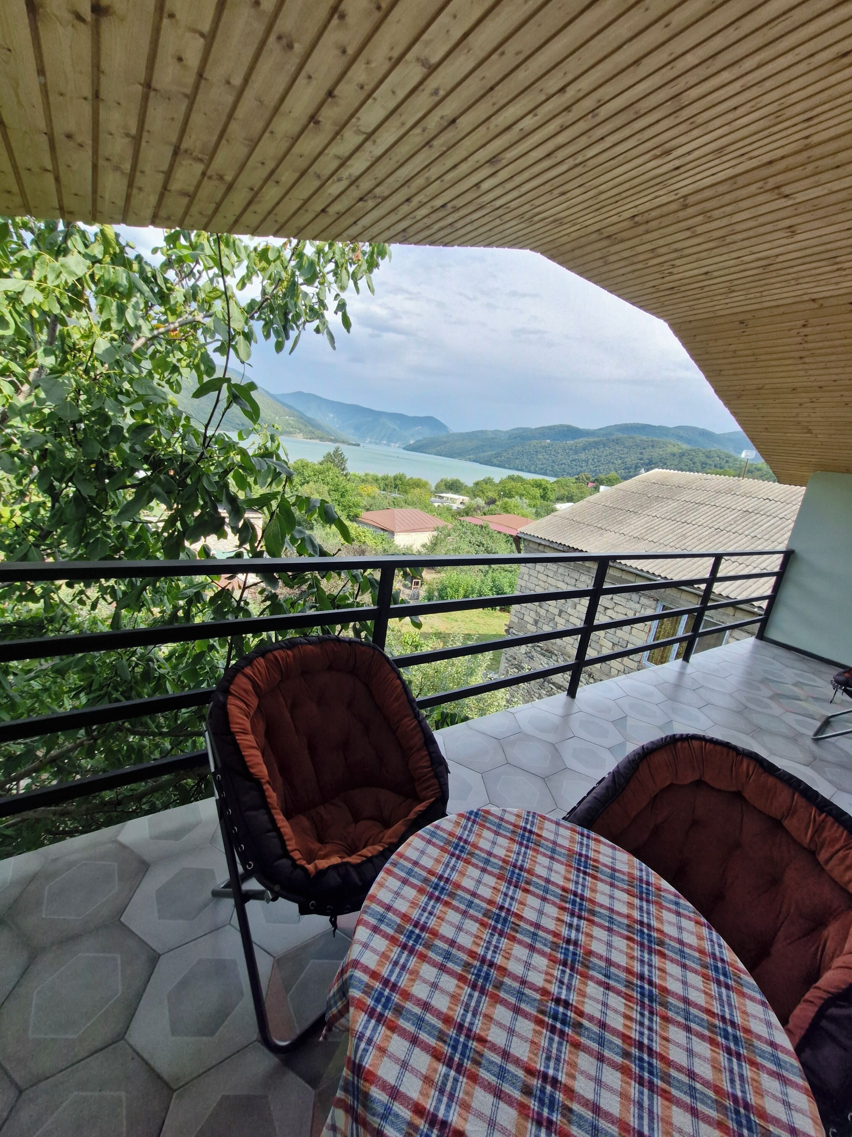 Ein Balkon mit Blick auf einen See und Berge, ausgestattet mit einem Stuhl und einem Tisch.