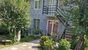 A stone pathway leading to a two-story building with a balcony and a staircase. - cozy house with stunning views of the Aragvi Valley (Ananuri)