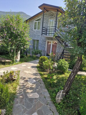 A stone pathway leading to a two-story building with a balcony and a staircase. - cozy house with stunning views of the Aragvi Valley (Ananuri)