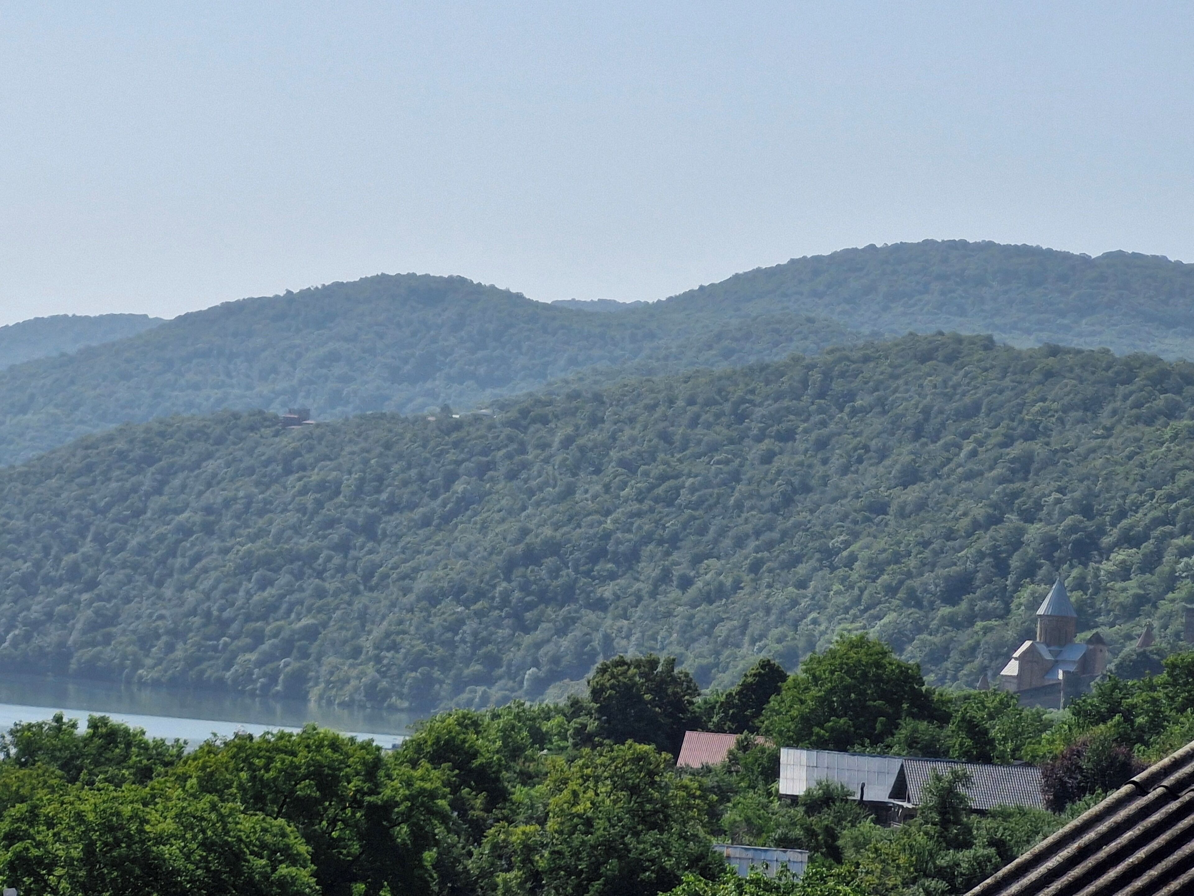 A mountainous landscape with a body of water and a building with a distinctive roof structure.