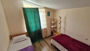 A room with two single beds, a wooden bench, a coat rack, and a window with curtains. - cozy house with stunning views of the Aragvi Valley (Ananuri)