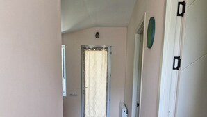 A hallway with patterned flooring, a door with a curtain, and a white wardrobe. - cozy house with stunning views of the Aragvi Valley (Ananuri)