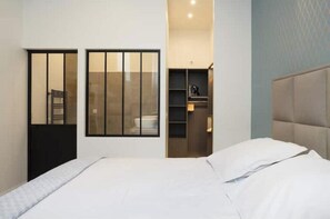 Ein Hotelzimmer mit Bett, Schrank, eingebautem Regal und Fenster.