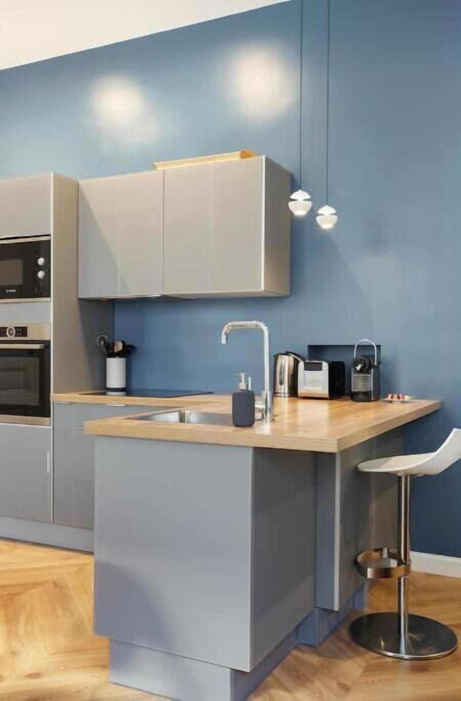 A modern kitchen with a built-in island, a sink, and a bar stool.