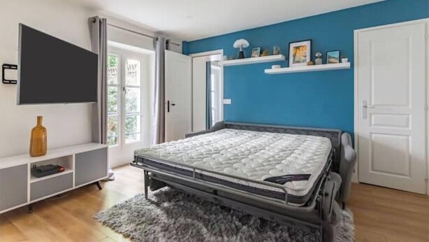 Ein Schlafzimmer mit Bett, Fernseher, Kleiderschrank und Tür.