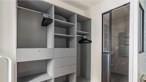 Ein begehbarer Kleiderschrank mit offenen Regalen, einer Kleiderstange und einem Schiebetürenschrank.