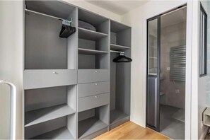 A walk-in closet with open shelving, a hanging rod, and a sliding door closet. - Renovated apartment between the Opera and the Louvre (Île-de-France)