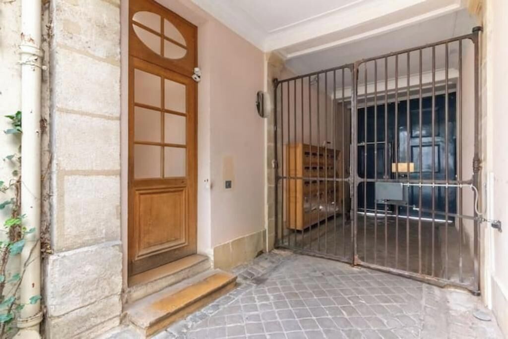 A gated entrance to a building with a wooden door and a metal gate.