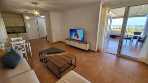 A living room with a sofa, a coffee table, a TV, and a balcony with a view. - El Rincon 12 - One Bed (Los Cristianos)