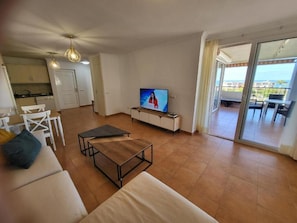 Ein Wohnzimmer mit einer Couch, einem Couchtisch, einem Fernseher und einem Balkon mit Blick.