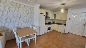 A compact kitchen with white cabinetry, a dining table with chairs, and a ceiling fan. - El Rincon 12 - One Bed (Los Cristianos)