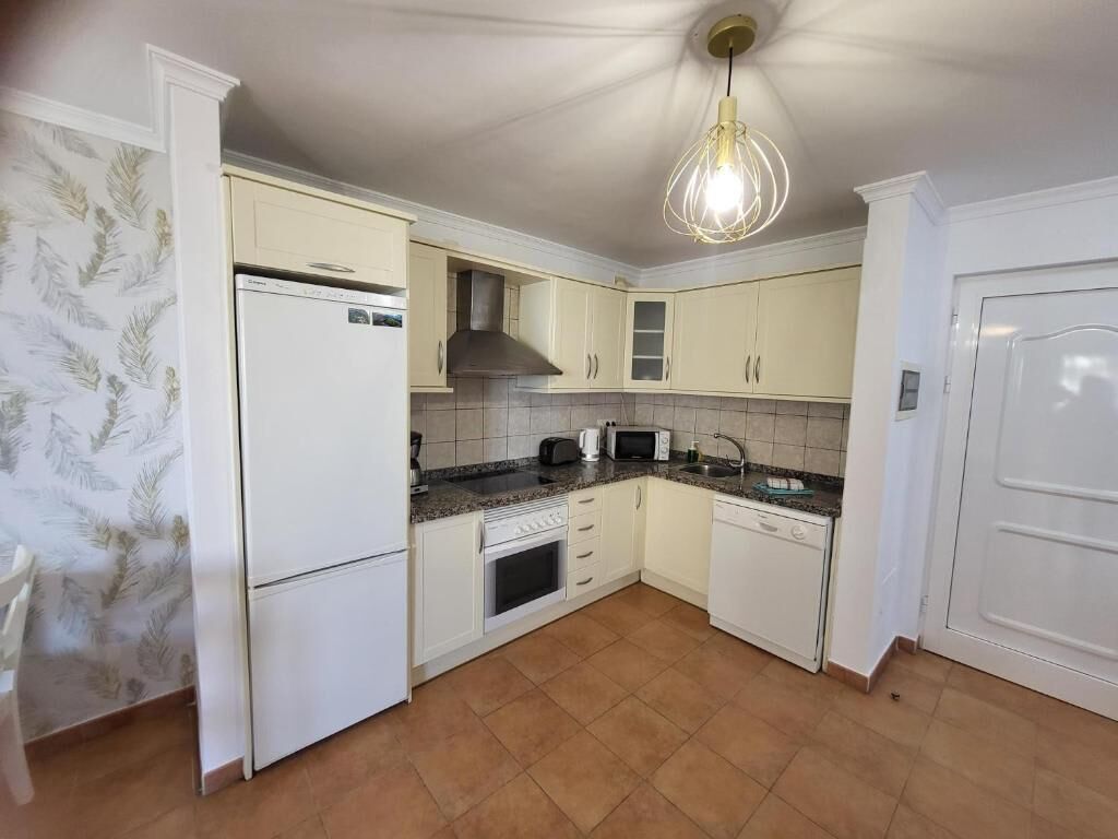 A kitchen with white cabinets, a built-in oven, a microwave, and a sink.