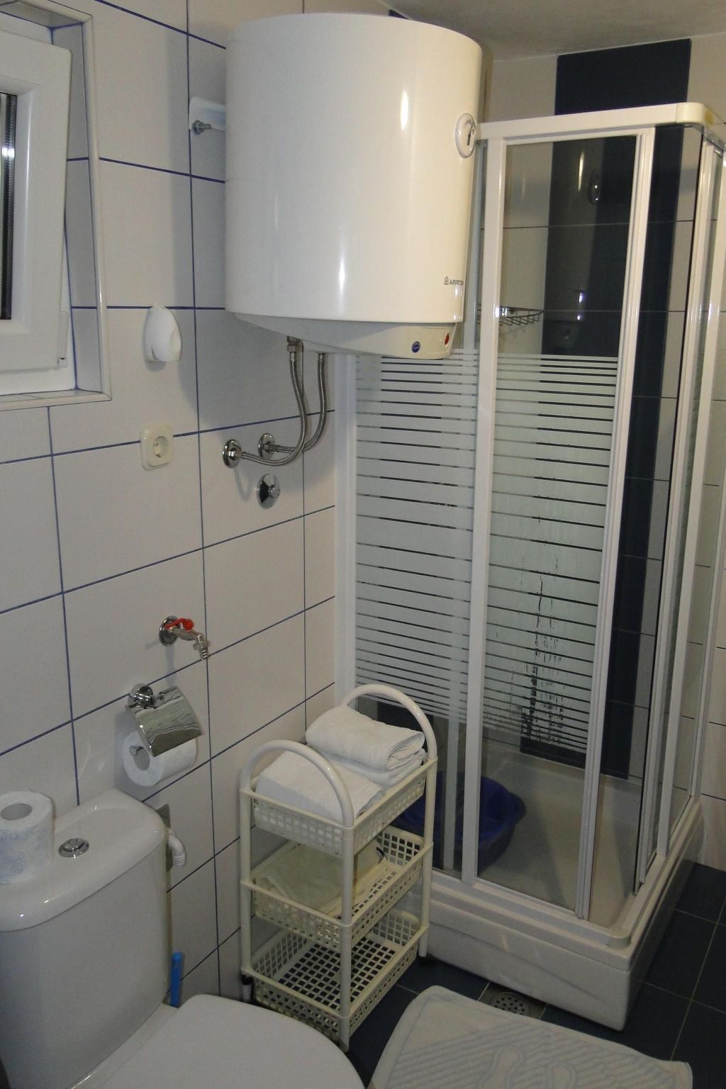 Ein Badezimmer mit Toilette, Duschkabine und Handtuchhalter.