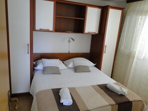 A hotel room with a bed, a bedside table, a wardrobe, and a window with curtains. - "Mir" mit Blick auf das Wasser by Interhome (Primošten)