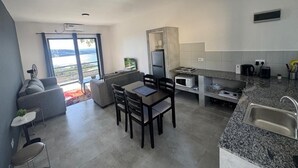 A modern kitchen with a dining area, built-in appliances, and a view through the glass door. - Apartment in siavonga (Siavonga)