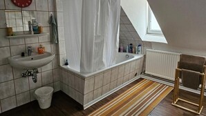 Uma casa de banho moderna com banheira, cortina de chuveiro, pia e porta-toalhas.